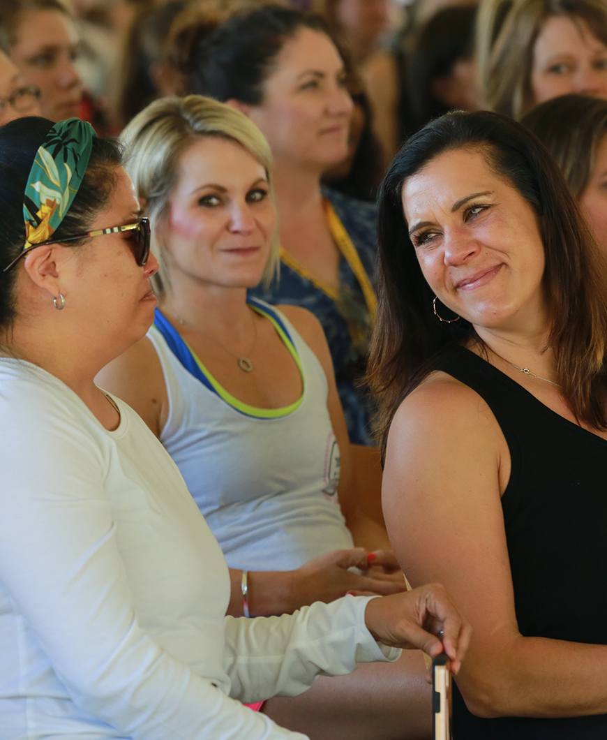 Women sitting in crowd listening to motivational speaker